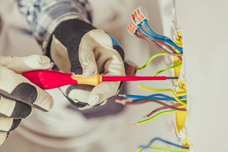 Electrician working on wall wiring and an electrical outlet